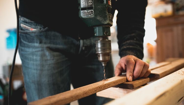 Man Drilling into a Wooden Board<br>